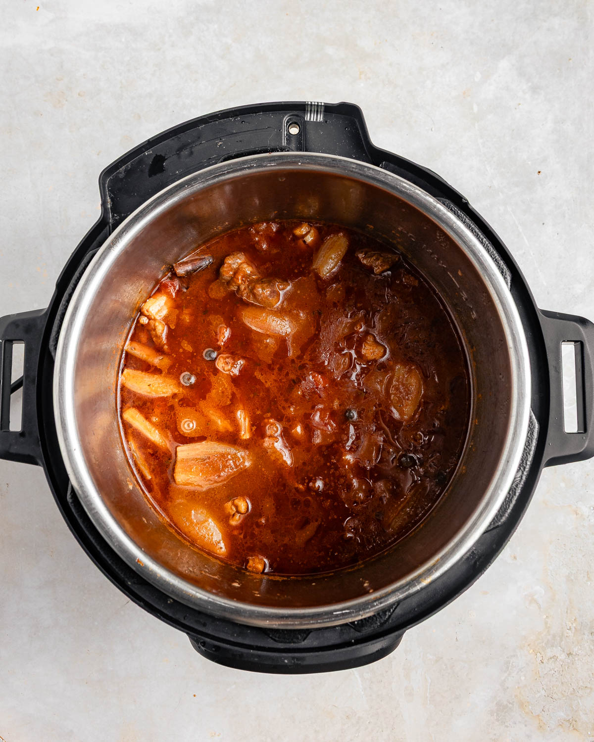 A top-down view of an Instant Pot with a cooked beef stifado before serving.